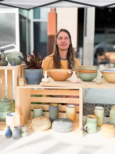 Joey Davenport behind his stall at a market, with pots on crates